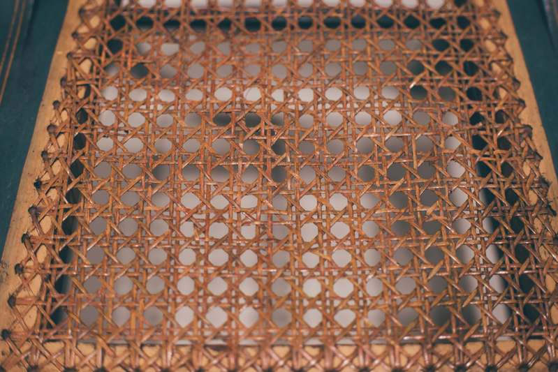 Founder working on restoring an antique wicker rocking chair in a sunlit workshop